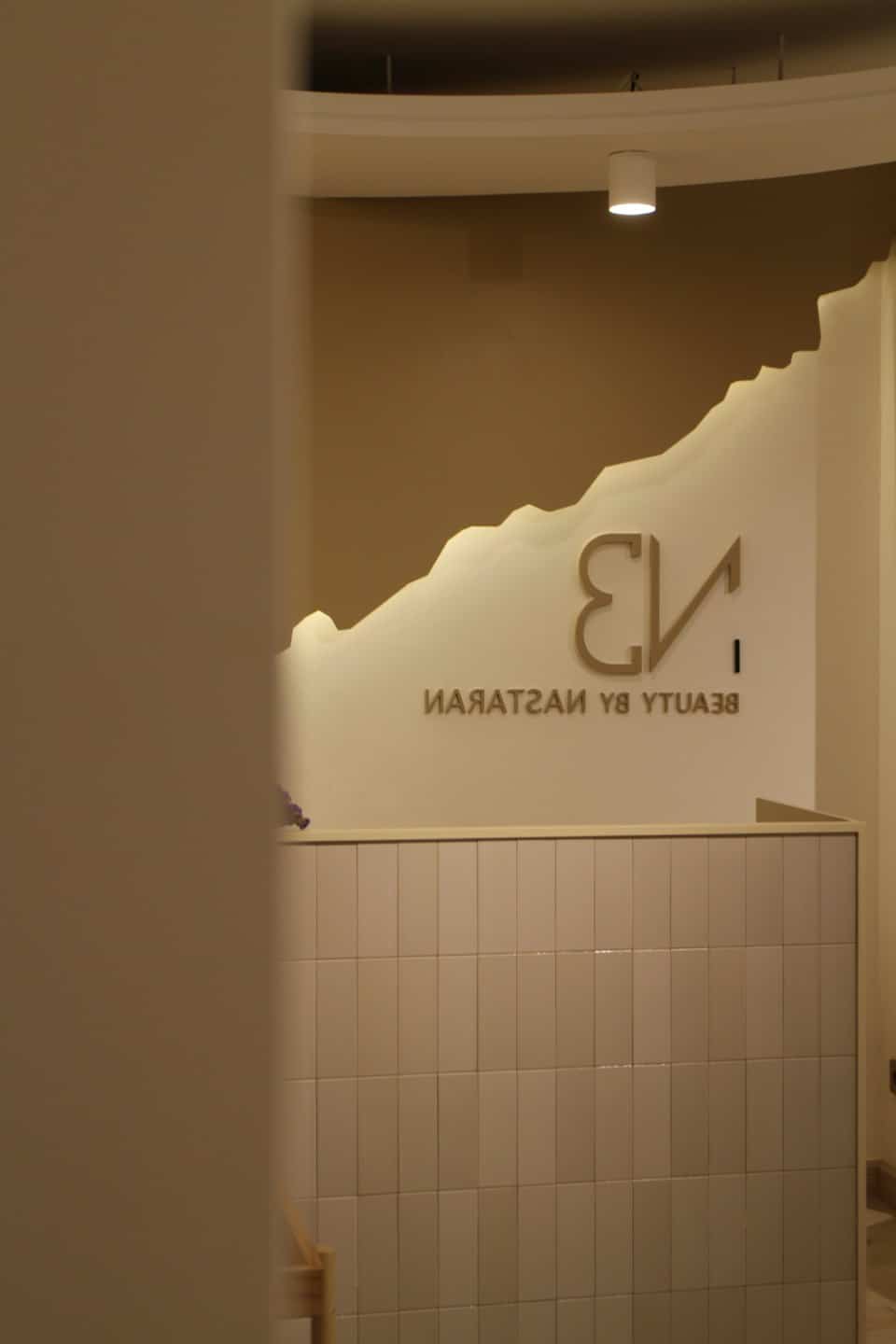Reception area with 'BEAUTY BY NASTARAN' logo on wall.